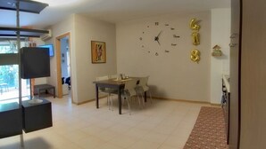 Zona pranzo con tavolo e sedie, una sveglia a parete e un piccolo quadro.