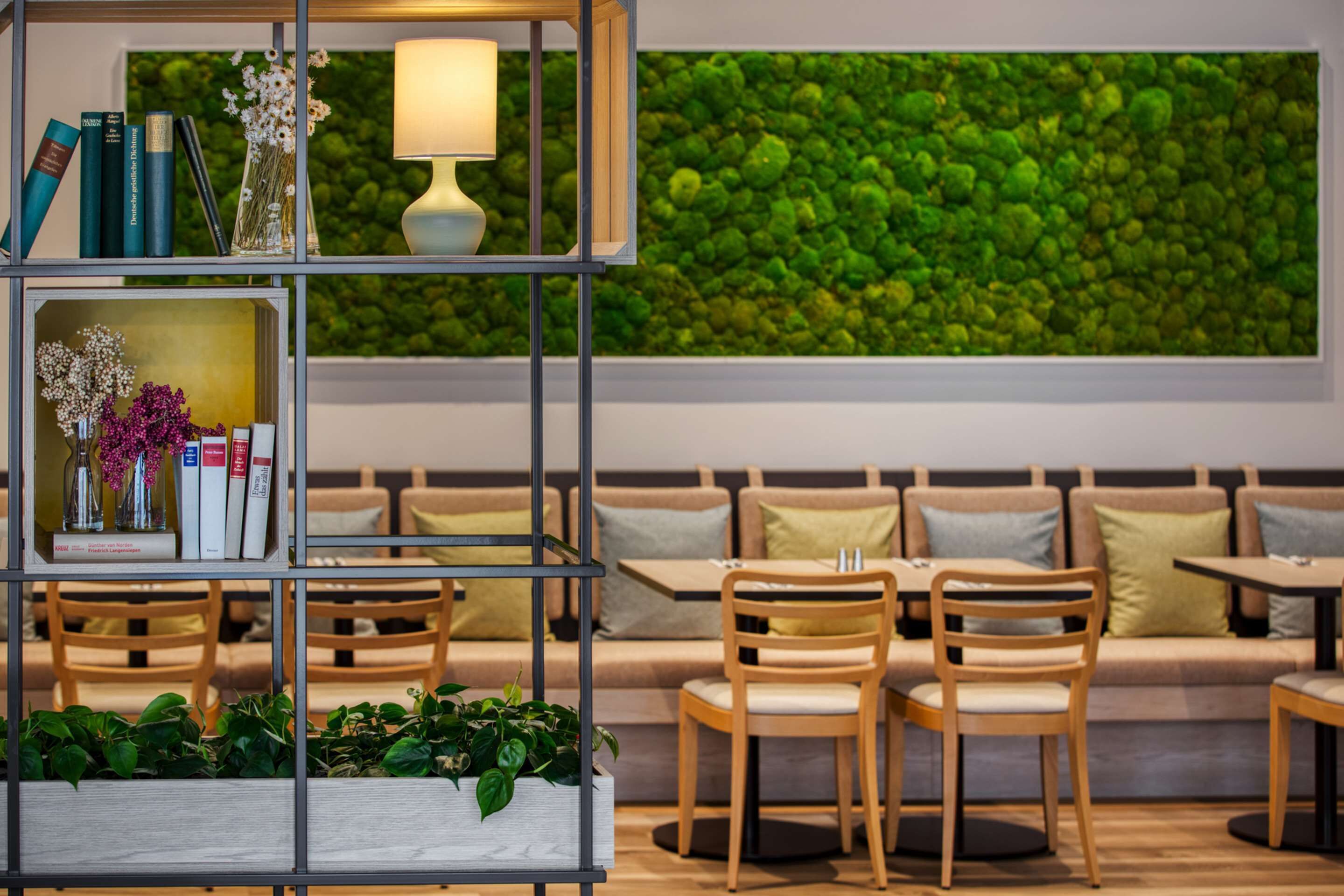 Un interior moderno con una pared verde, una estantería y zonas de estar.