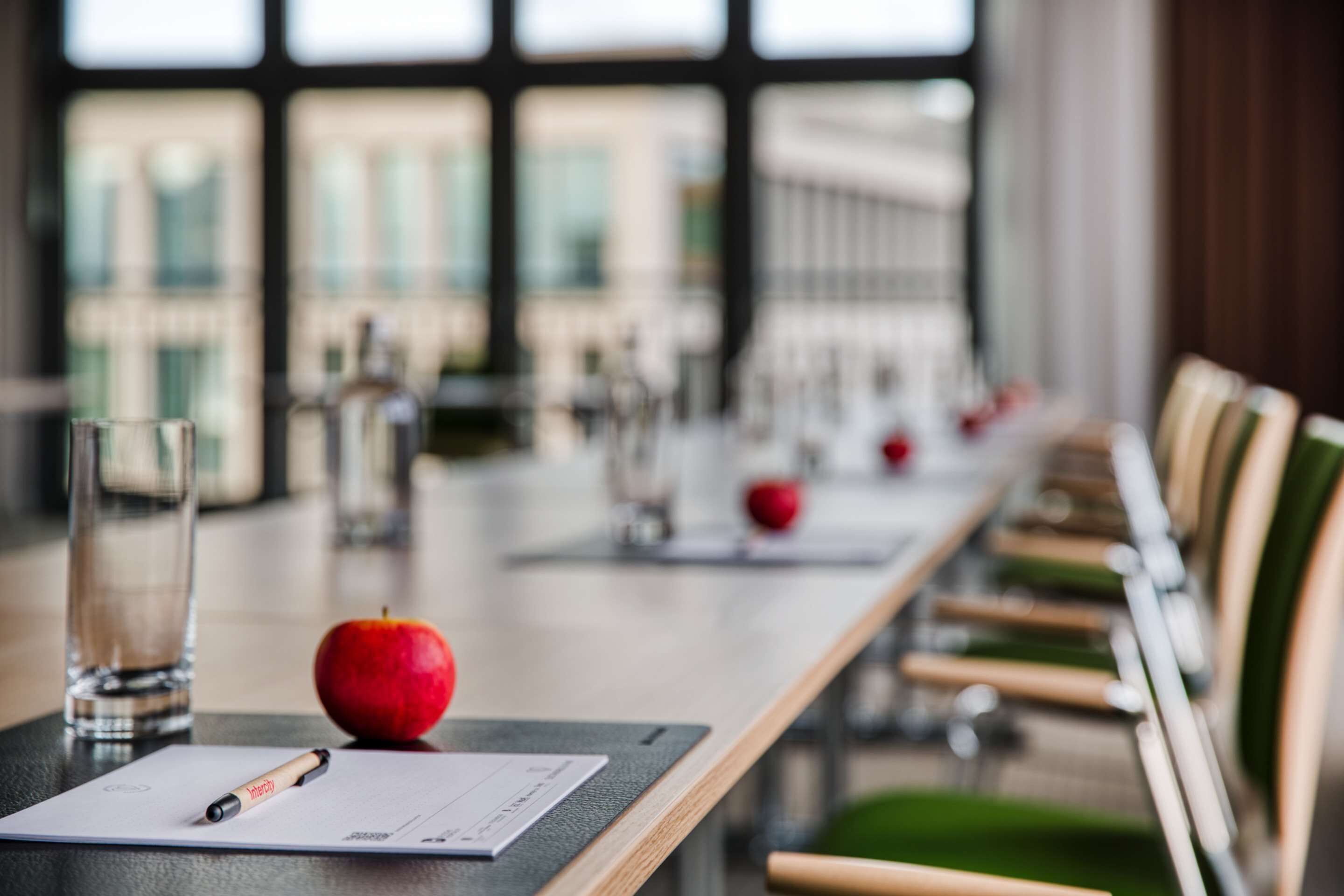 Une table de conférence avec un document, un stylo et une pomme.