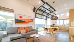 A modern living room with a grey sofa, a coffee table, and a dining area with a yellow table and chairs. - Holiday Escape!!! Pool, Hot Tub, Game Room, Fire Pit (Vista)