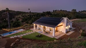 A modern house with a solar panel roof, a swimming pool, and a patio area with string lights. - Holiday Escape!!! Pool, Hot Tub, Game Room, Fire Pit (Vista)