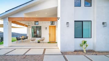 A modern house with a patio, outdoor seating, and a cactus in the garden.