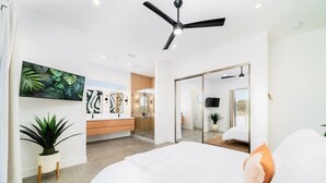 A modern bedroom with a large bed, a ceiling fan, a bathroom with a glass door, and a large mirror. - Holiday Escape!!! Pool, Hot Tub, Game Room, Fire Pit (Vista)