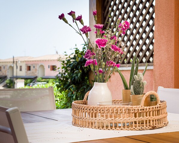 A wicker basket with a vase of pink flowers and a cactus on a table.