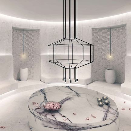 A modern interior with a marble table, geometric pendant light, and hexagonal patterned walls.