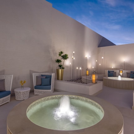 A modern outdoor lounge area with a central water feature, seating arrangements, and ambient lighting.