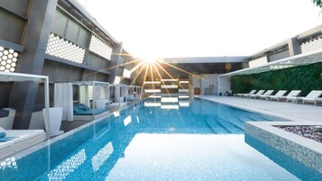 Una piscina al aire libre, sombrillas, sillones reclinables de piscina