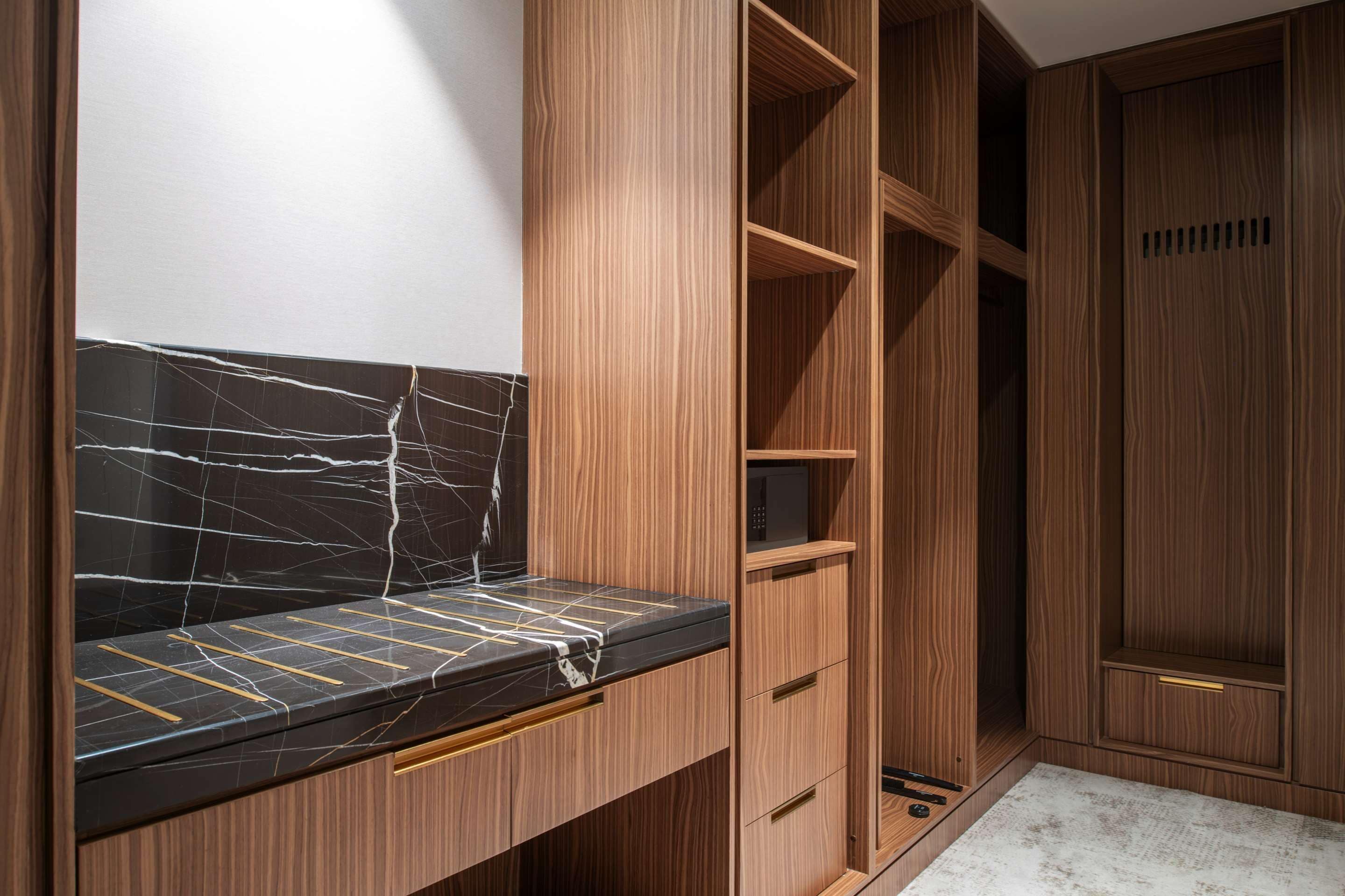 A wooden vanity with a marble countertop and a mirror.