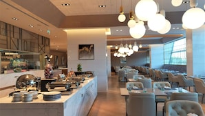 A modern restaurant with a buffet area, dining tables, and a bar. - Steigenberger Hotel Doha (Doha)