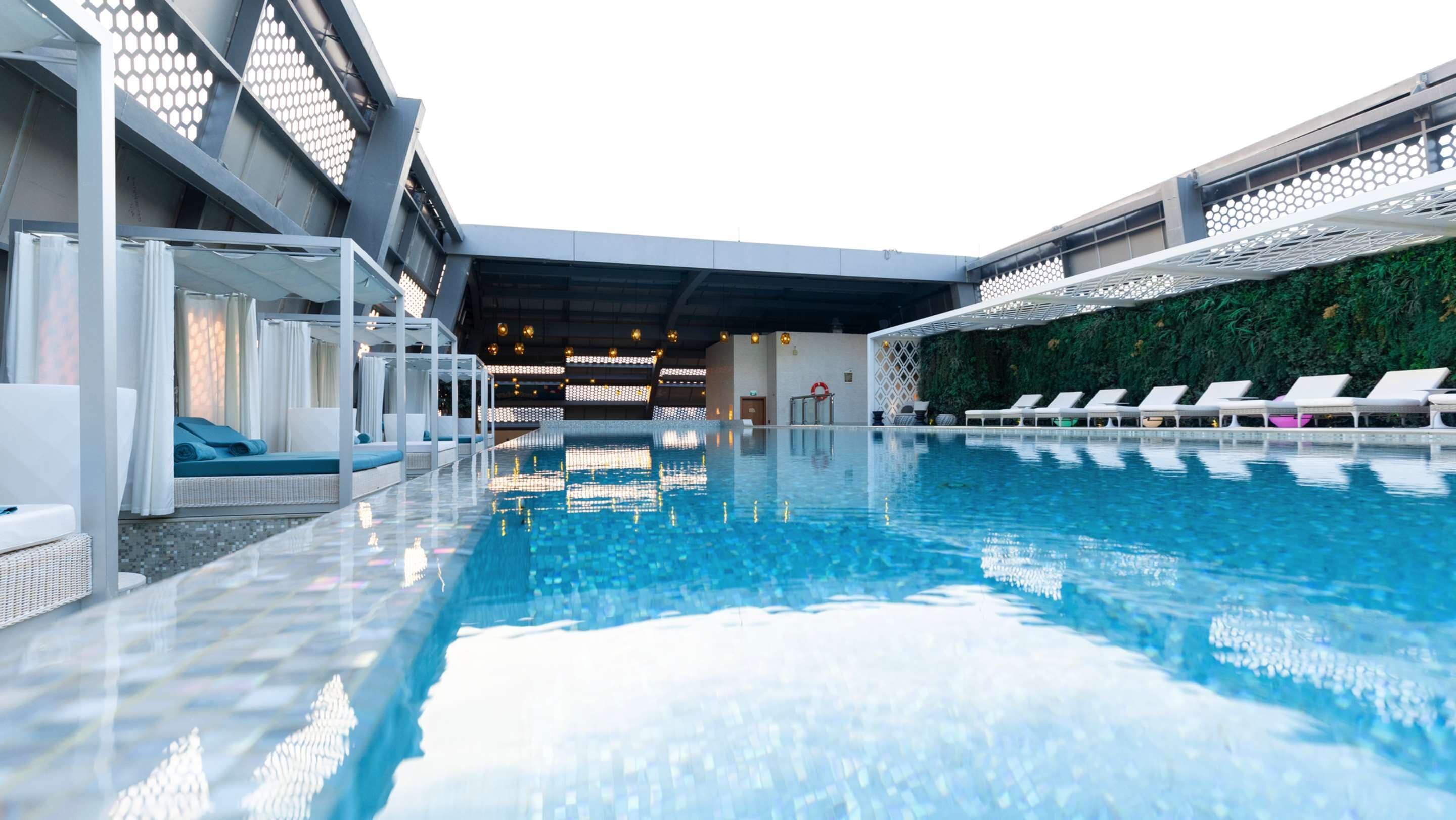 Una piscina interior moderna con sillones de descanso y techo de vidrio.