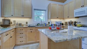A kitchen with wooden cabinets, a granite countertop, and a window. - Charming 2BR Uptown Cottage - Artsy & Vibrant! (St. Augustine)