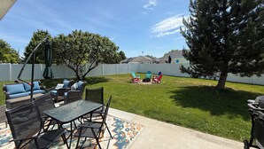 A patio with outdoor furniture, a swing, and a tree.