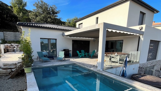 A modern house with a swimming pool, outdoor seating, and a covered patio area. - Villa Avec Piscine, Jacuzzi et vue Imprenable sur la Garigue (Saint-Paul-et-Valmalle)