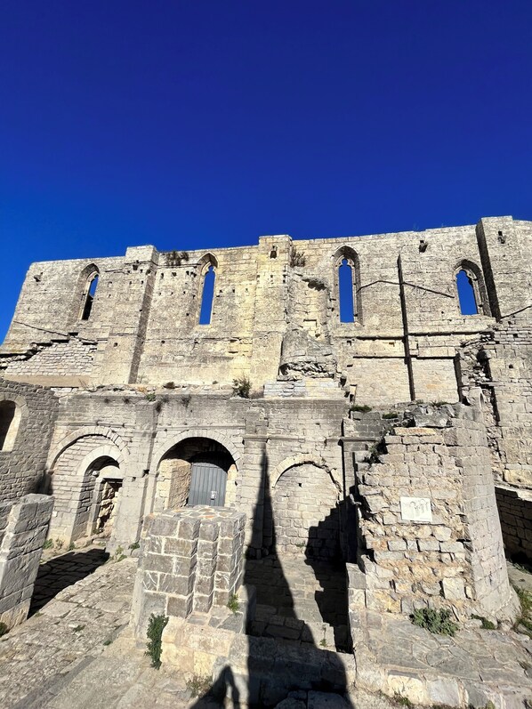 An ancient stone building with arched windows and a central doorway.