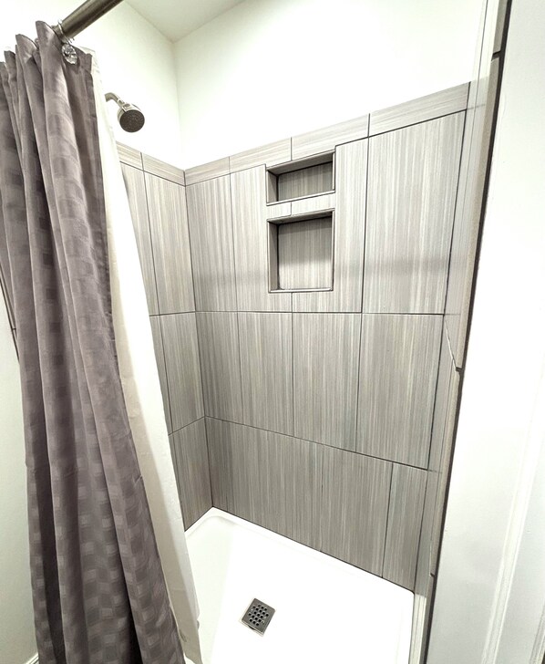 Ein Badezimmer mit Dusche, Handtuchhalter und einem kleinen Fenster.