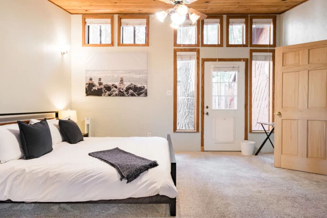 Een slaapkamer met een bed, een plafondventilator, een raam en een deur.
