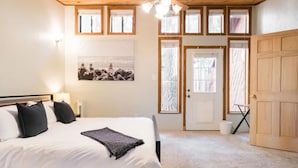 Ein Schlafzimmer mit Bett, Deckenventilator, Fenster und Tür.