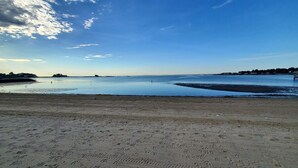 A beach with a clear sky, calm water, and a distant shoreline. - The Fred Deluxe 7 BR by I95, Train, HarborVw, Stamford Beaches & Workspace

 (Stamford)