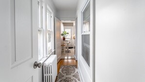 A hallway with white walls, a radiator, and a patterned rug. - The Fred Deluxe 7 BR by I95, Train, HarborVw, Stamford Beaches & Workspace

 (Stamford)