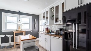 A modern kitchen with white cabinets, a black refrigerator, and a wooden countertop. - The Fred Deluxe 7 BR by I95, Train, HarborVw, Stamford Beaches & Workspace

 (Stamford)