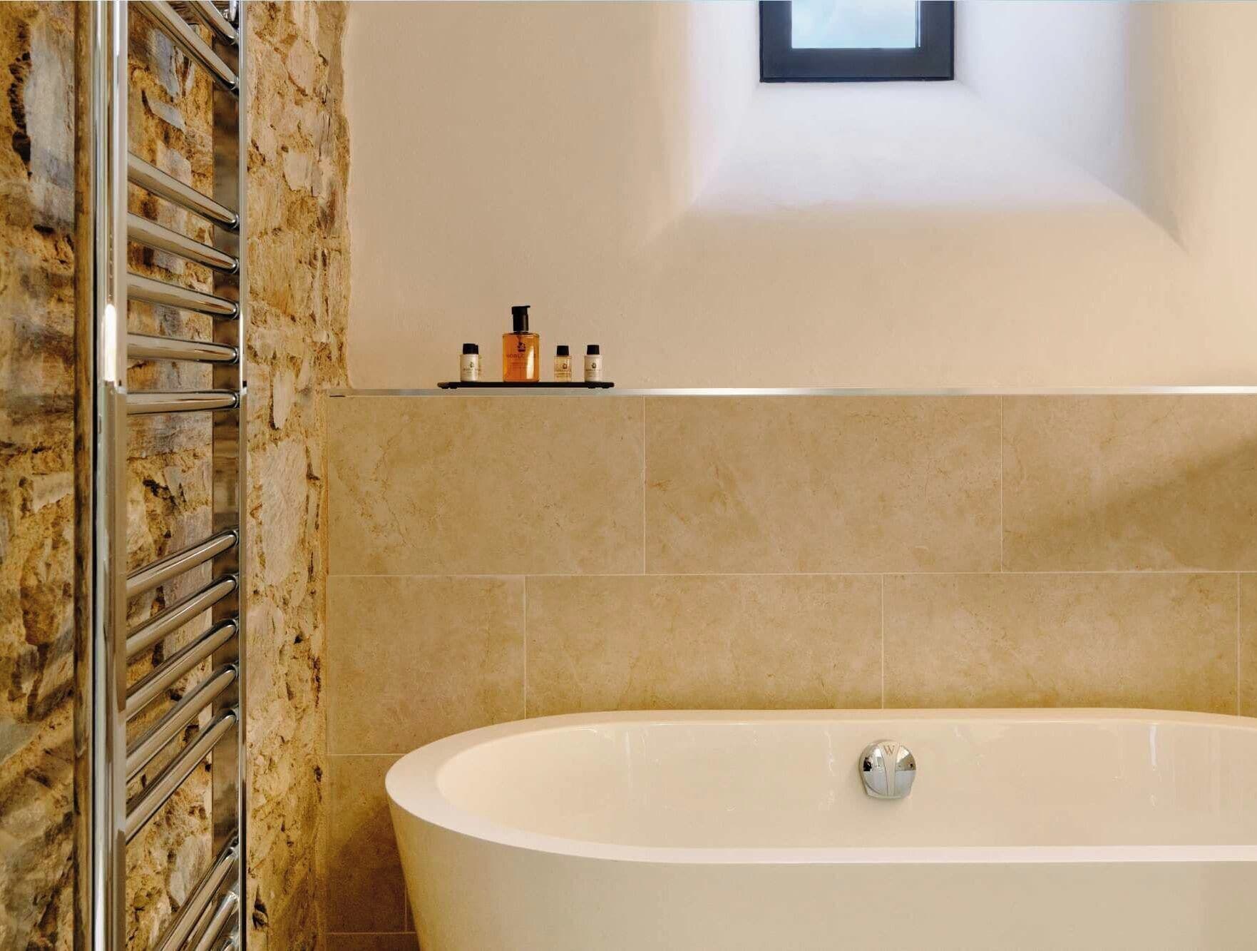 A bathroom with a freestanding bathtub, a towel rack, and a shelf with toiletries.