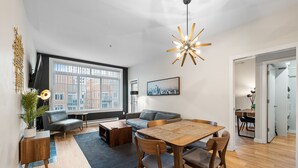 Un salon moderne avec un coin repas, de grandes fenêtres et une vue sur la ville.