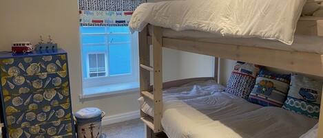 A bunk bed room with a window, a dresser, and a toy car on the dresser.