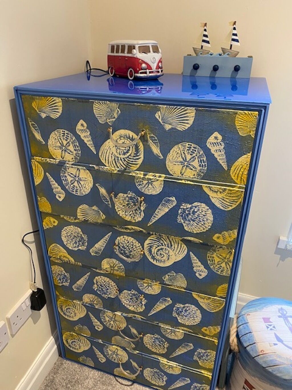 A cabinet with a blue top and a patterned surface featuring various shell designs.