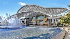 A modern building with a unique curved roof structure and a central water feature. - Hotel Puerto Valdes (San Juan)