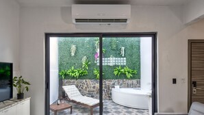 A modern living room with a large sliding glass door leading to a patio area with a stone wall and greenery. - Hotel Puerto Valdes (San Juan)