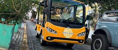 A yellow bus with "PUERTO VALDES" on the back, parked on a cobblestone street.
