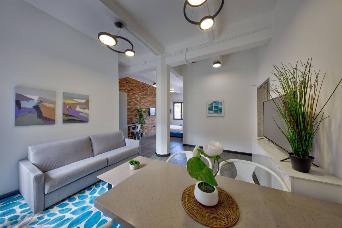 A modern living room with a grey sofa, a coffee table with a potted plant, and artwork on the walls.