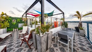 A rooftop terrace with a glass enclosure, outdoor seating, and potted plants. - Hotel Puerto Valdes (San Juan)