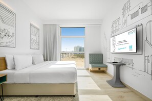 Ein modernes Hotelzimmer mit einem großen Bett, einer Sitzecke und einem Fernseher, der eine Willkommensnachricht anzeigt.