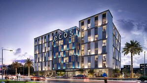 Een modern hotel met een opvallend 'ecos Hotel' bord, bestaande uit een meerhoog gebouw met grote ramen en een glazen gevel.