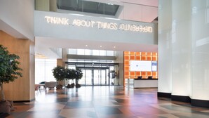 Un vestíbulo moderno con un letrero que dice 'Think About Things Beautifully', una recepción y un área de registro.