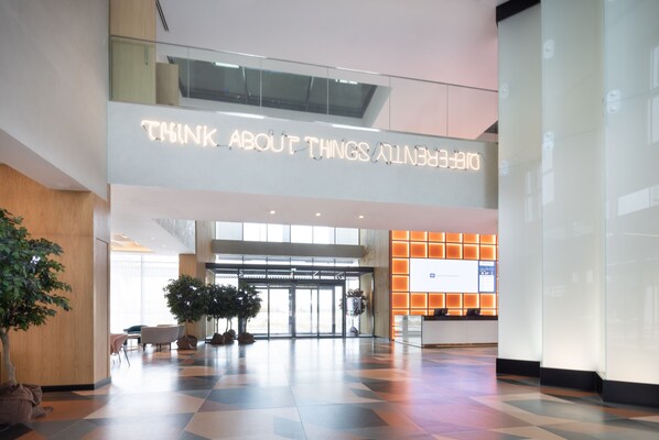 Un hall d’entrée moderne avec une pancarte portant l’inscription « Pensez à la beauté dans tout ce que vous faites », un comptoir d’accueil et un espace dédié à l’enregistrement des clients.
