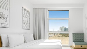 Een moderne slaapkamer met een groot bed, uitzicht op het strand en een balkon.