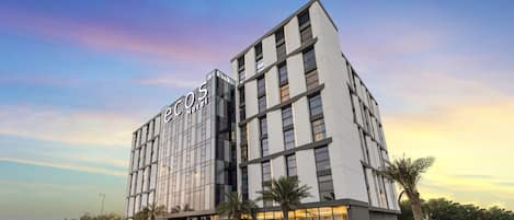 A modern hotel building with a prominent sign reading 'ecos Hotel'.