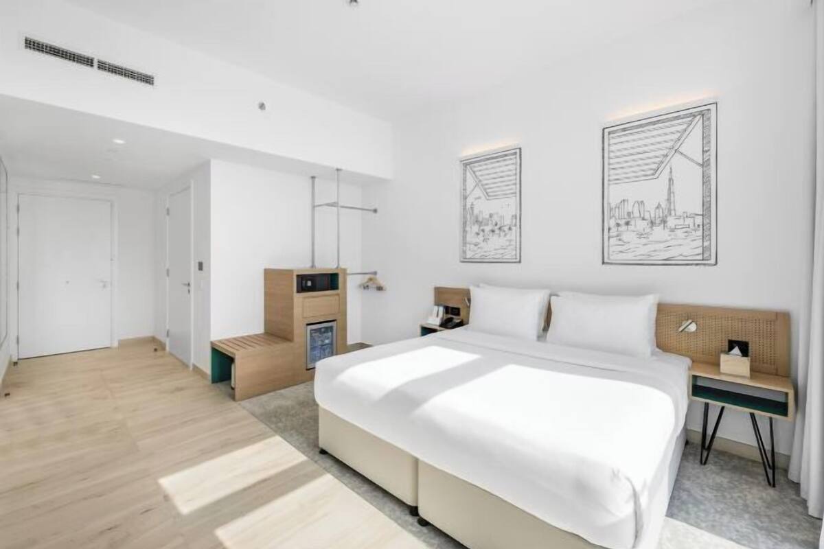 Ein modernes Hotelzimmer mit einem großen Bett, Nachttischen, einem Schreibtisch und Kunstwerken an den Wänden.