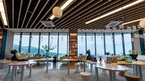 Une bibliothèque moderne dotée de grandes fenêtres, d’étagères et d’espaces aménagés pour s’asseoir.