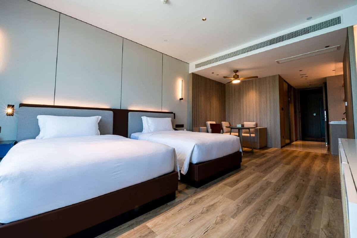 Ein Hotelzimmer mit zwei Betten, einem Schreibtisch und einem Sessel.