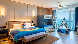 Une chambre d’hôtel moderne dotée d’un grand lit, d’un bureau, d’une armoire, d’une tente et offrant une vue sur la mer.