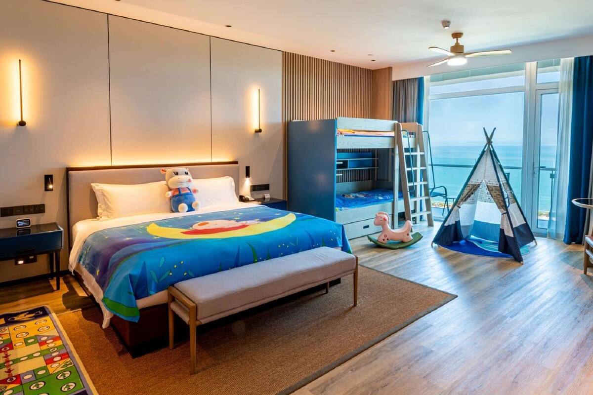 Ein modernes Hotelzimmer mit einem großen Bett, einem Schreibtisch, einem Kleiderschrank, einem Zelt und Meerblick.
