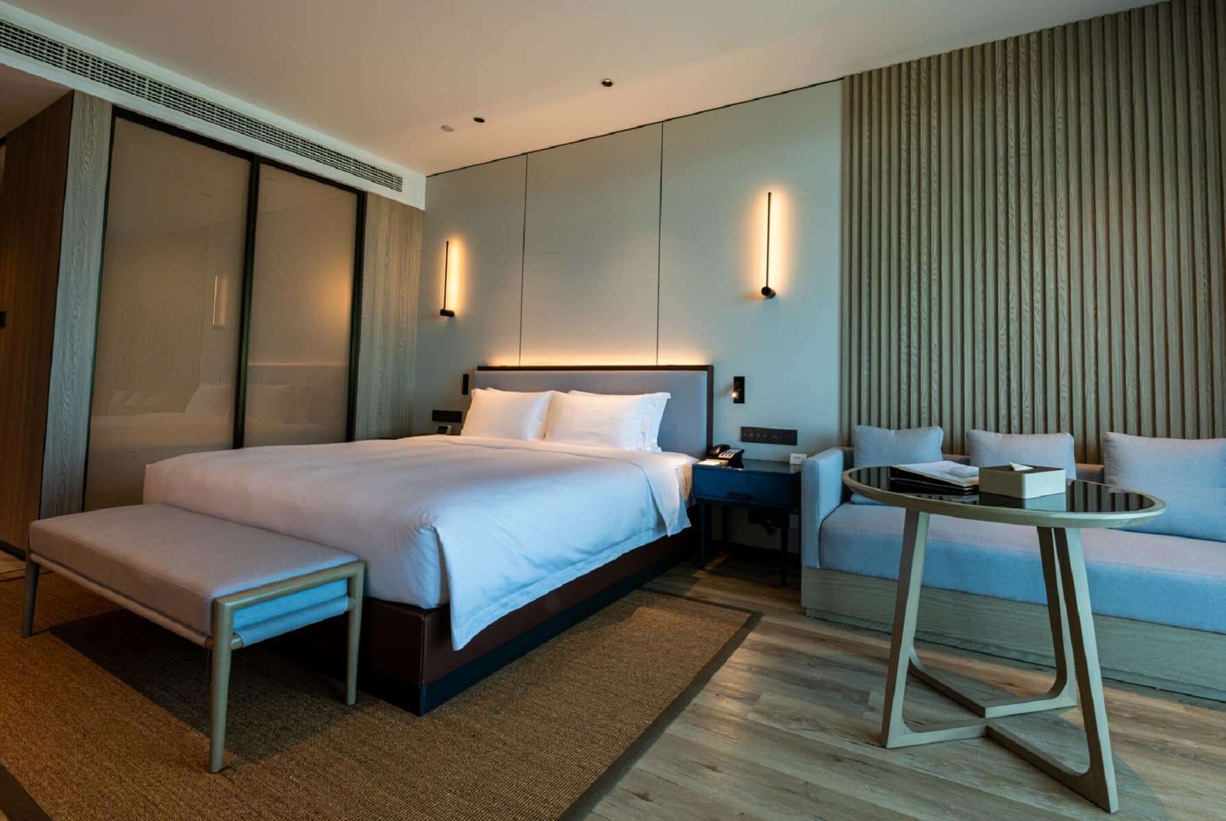 Une chambre d’hôtel moderne équipée d’un grand lit, d’un bureau, d’une chaise et d’un canapé.