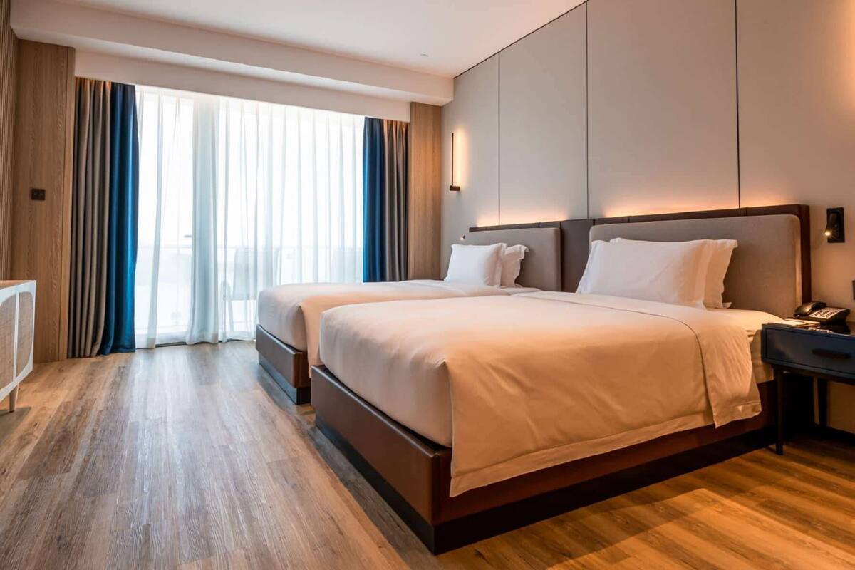 Ein Hotelzimmer mit einem großen Bett, einem Schreibtisch mit Telefon und Blick aus dem Fenster.