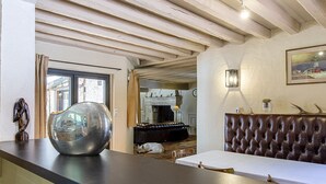 A modern interior with a large glass bowl on a counter, a leather sofa, and a fireplace in the background.