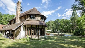 A house with a unique curved structure, a chimney, and a small pool area.