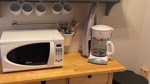 A kitchen area with a microwave, coffee maker, and storage shelves. - The Guest Cottage in Lake City (Lake City)