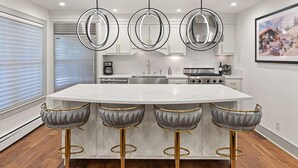 A modern kitchen with a central island, bar stools, pendant lights, and a large window. - BRIGHT, Renovated, In the Heart of Aspen Walkable (Aspen)